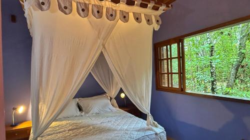 a bedroom with a canopy bed with a window at Pousada Taman Baru in Pirenópolis