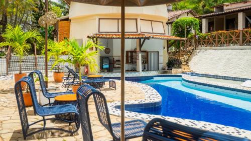 a patio with chairs and an umbrella next to a pool at Pousada Bicho Preguiça in Pipa