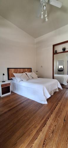 a bedroom with a large white bed and wooden floors at Monoambiente en Puerto Nuevo in Concepción del Uruguay