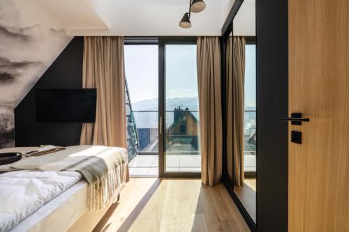 a bedroom with a bed and a large window at Salamandra Luxury Villas with Jacuzzi by BQQK in Kościelisko