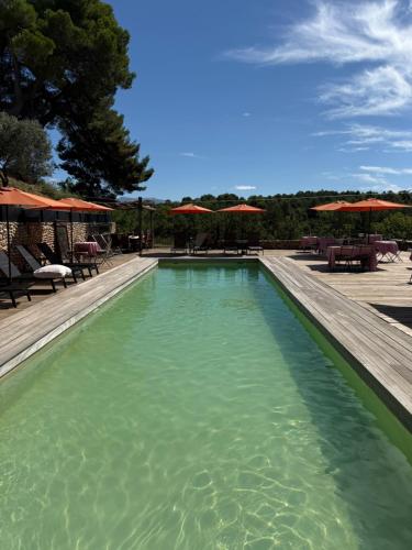 a swimming pool with tables and umbrellas on a patio at Lodges en pleine nature in Riez
