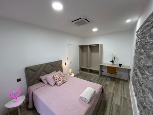 a bedroom with a pink bed and a stone wall at Victoria 1942 in Funchal