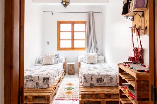 a room with two beds and a tv and a window at Appart Ayoub in Essaouira
