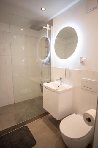 a bathroom with a toilet and a sink and a mirror at Cozy apartment with pool I U-Bahn in Munich