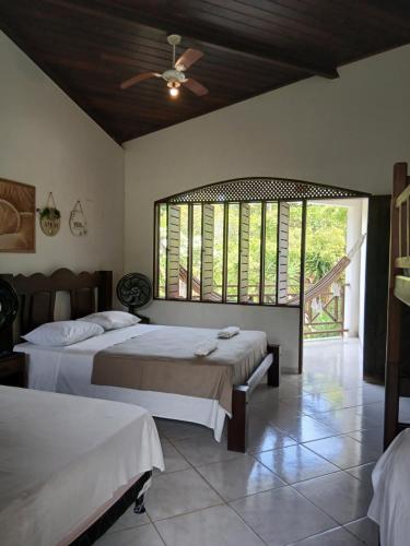 a bedroom with two beds and a large window at Casa charme pipa in Pipa