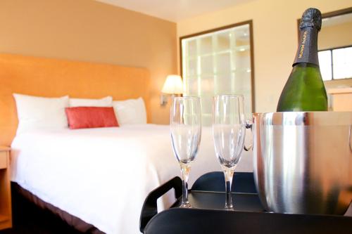 a bedroom with a bed and two wine glasses on a table at Regency Inn in Vallejo