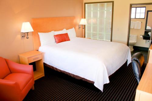 a hotel room with a large bed and a red chair at Travelodge by Wyndham Vallejo in Vallejo