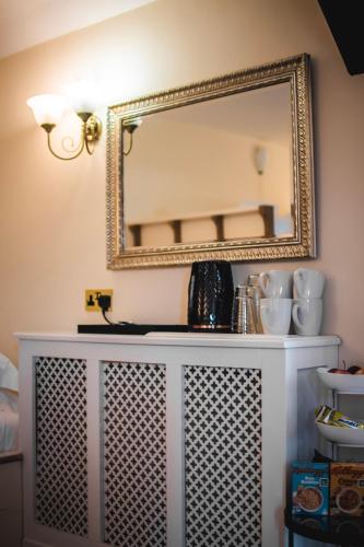 a mirror on a wall above a white dresser at Dykeneuk rooms in Hartburn
