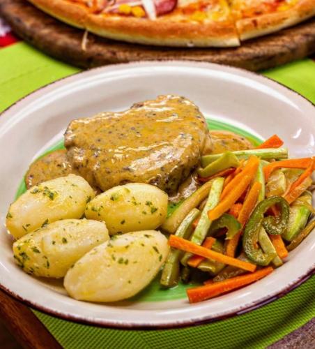 a plate of food with meat and potatoes and vegetables at Hotel Kariña Punta de Mata in Punta de Mata