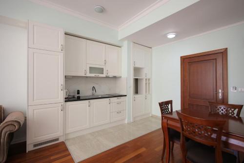 a kitchen with white cabinets and a dining room table at Apartman A4 - Dvorac Belimarkovic in Vrnjačka Banja