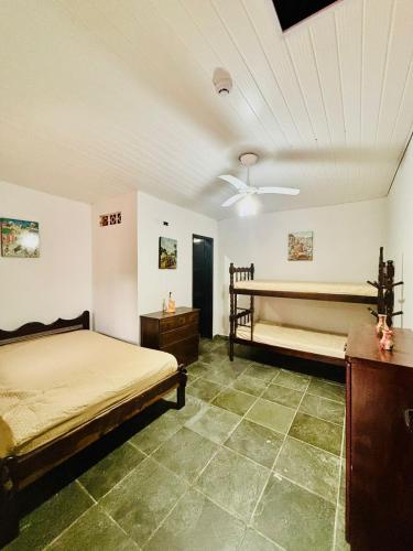 a bedroom with two beds and a ceiling fan at Pousada NativaMar in Guaratuba