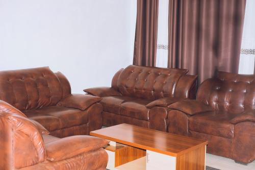 a living room with two brown leather couches and a table at Davidson's guest house in Kayonza
