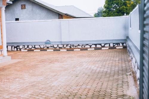 a fence in front of a house with a brick driveway at Davidson's guest house in Kayonza