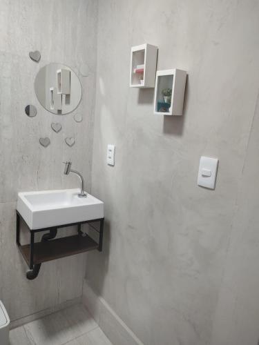 a white bathroom with a sink and a mirror at Quarto Paulínia 2 in Paulínia