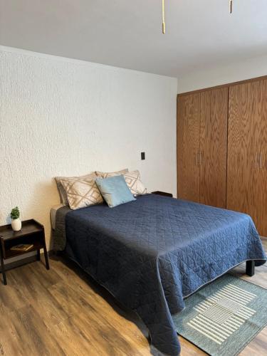 a bedroom with a bed with a blue comforter at Deluxe Loft Air Conditioning Downtown Parking in Tepatitlán de Morelos