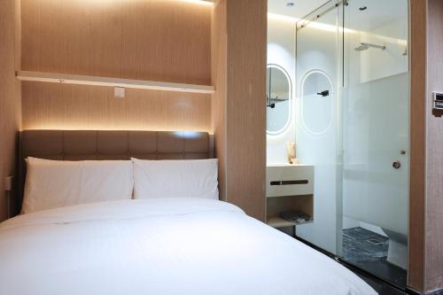 a bedroom with a white bed and a shower at Aura Hotel Purvis in Singapore