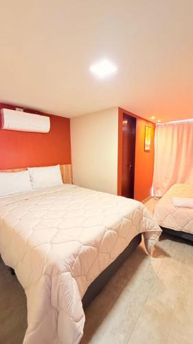 a bedroom with two beds and a red wall at CASARÃO SUíTES MARAGOGI in Maragogi