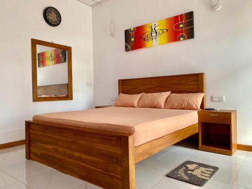 a bedroom with a wooden bed with a clock on the wall at Coral Waves Inn - Pasikuda in Kalkudah