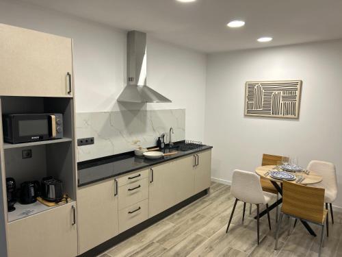 a kitchen with white cabinets and a table with chairs at Victoria 1942 in Funchal