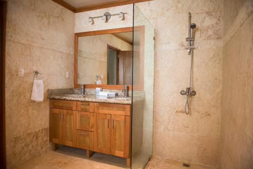 a bathroom with a sink and a shower with a mirror at Hispaniola Luxury Ocean Front Condo in Sosúa