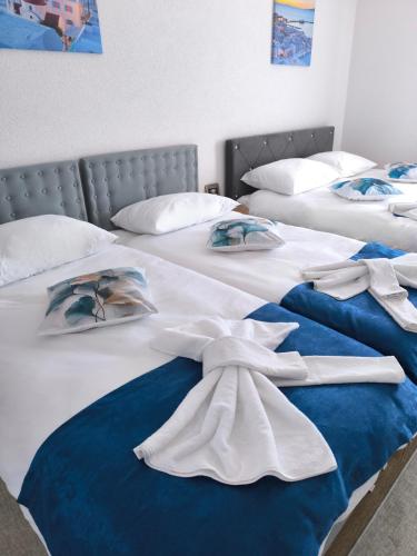 two beds with white sheets and towels on them at TOKIs apartmani in Mrkonjić Grad
