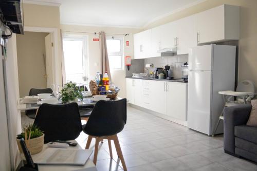 a kitchen with a table and a white refrigerator at Azorean Stays T1-Relaxing 1-Bedroom Retreat Near São Miguel Highlights in Lomba da Cruz