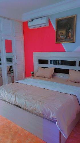 um quarto com uma cama grande com uma parede vermelha em Emirimmo em Dakar