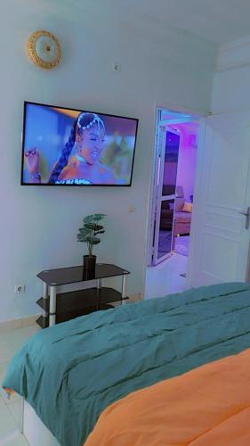 ein Schlafzimmer mit einem Bett und einem Fernseher an der Wand in der Unterkunft Emirimmo in Dakar