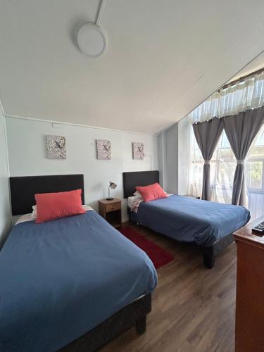 two beds in a room with blue and pink at Residencial Mar y Sol in Laraquete