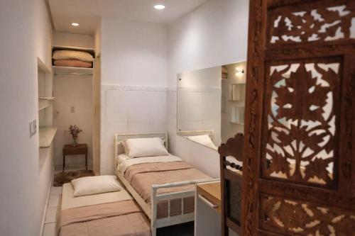 a small room with two beds and a wooden door at Costa Family-Casa Costa (downtown Santa Rita) in Santa Rita do Sapucaí