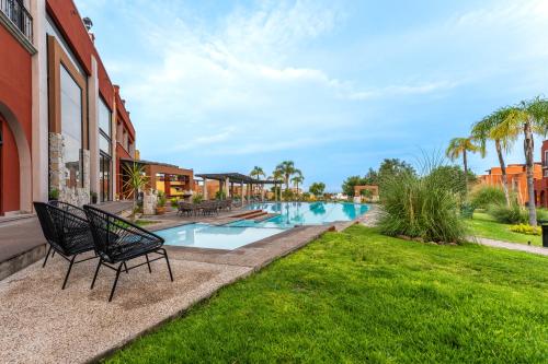 a swimming pool with two black chairs next to a building at Krystal Grand Residences & Villas San Miguel de Allende in San Miguel de Allende