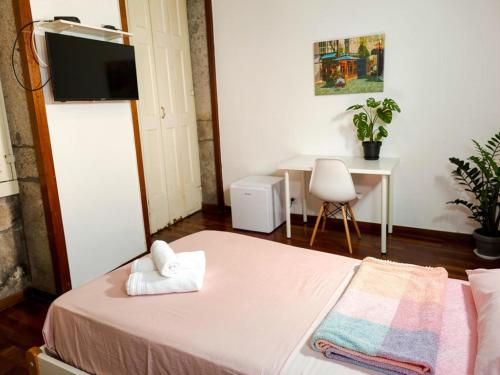 a small room with a bed and a table with a chair at Guest House Sir Manuel - Unidade São Vicente in Braga