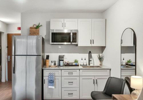 a kitchen with white cabinets and a stainless steel refrigerator at Modern Midtown Studio and Private Balcony in Raleigh