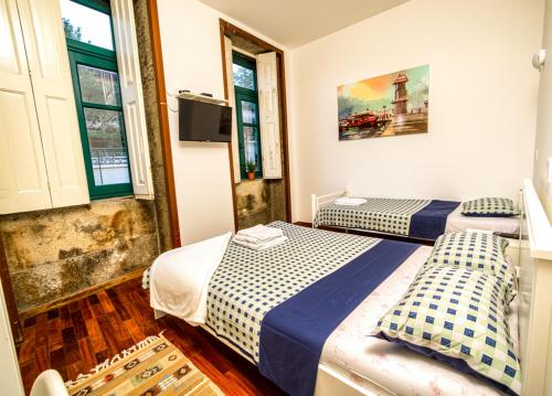 two beds in a room with two windows at Guest House Sir Manuel - Unidade São Vicente in Braga