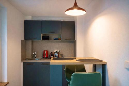 a kitchen with blue cabinets and a table and chairs at SOLO by Tendo Stay - Comfort Housing in Falkensee