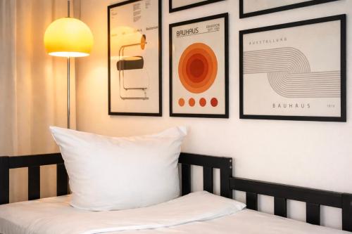 a bed with a white pillow and some framed pictures at SOLO by Tendo Stay - Comfort Housing in Falkensee