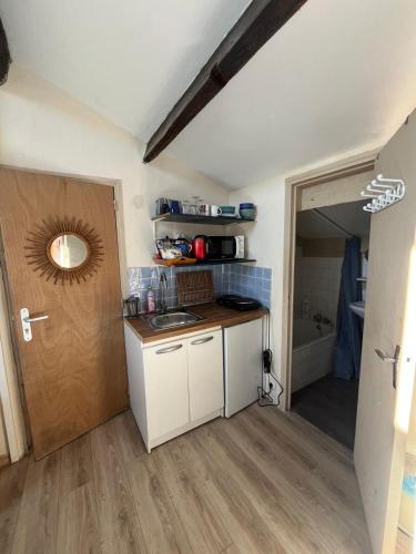 una piccola cucina con un lavello e una porta di studio haki a Sète