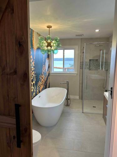 a bathroom with a tub and a shower and a chandelier at The Marmalade Motel in Port Dufferin