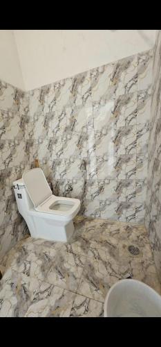 a bathroom with a toilet and a stone wall at Chill and Cheers Resort in Dehradun