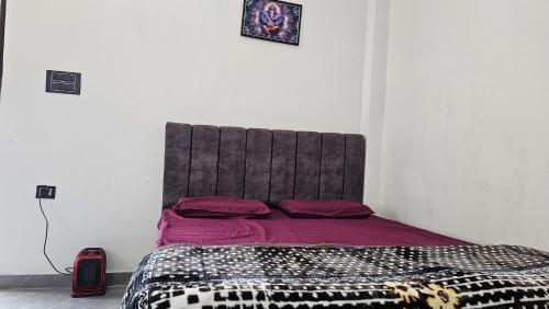 a bedroom with a bed with purple sheets and red pillows at Chill and Cheers Resort in Dehradun