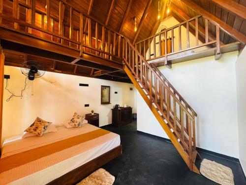 a bedroom with a bed and a wooden staircase at Sinharaja Brook Cabana in Deniyaya