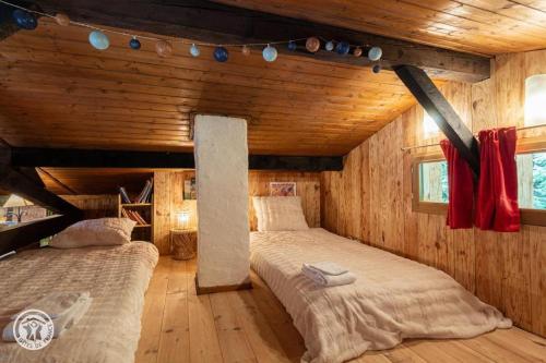 two beds in a room with wooden walls at Petit chalet l Authentique Annecy in Dingy-Saint-Clair