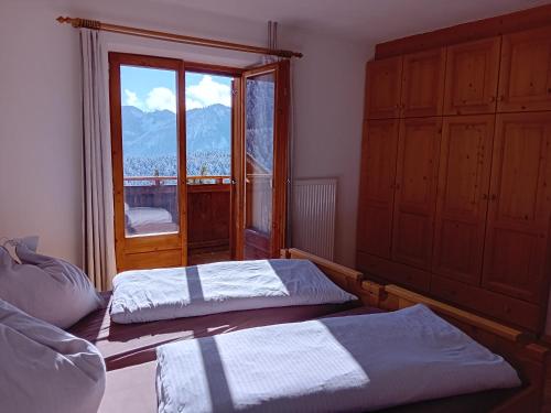 a bedroom with two beds and a large window at Lü de Terza in San Vigilio Di Marebbe