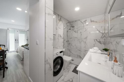 a white bathroom with a sink and a washing machine at OurMadeira - Terrace Sea Apartments in Ribeira Brava
