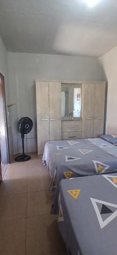 a bedroom with three beds and a chair in it at Casa da vila in Imbituba