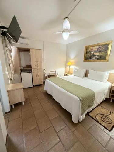 a bedroom with a large white bed and a television at Hotel Mirante in Barra Velha