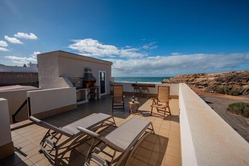 ein Balkon mit Stühlen und einem Tisch und das Meer in der Unterkunft Salitre in Ajuy