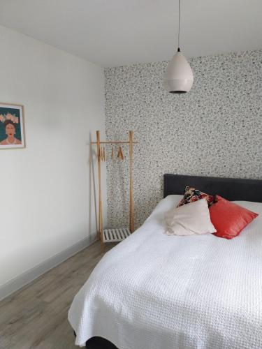 a bedroom with a white bed with red and white pillows at Maisonette Syl' -vie in Cognac