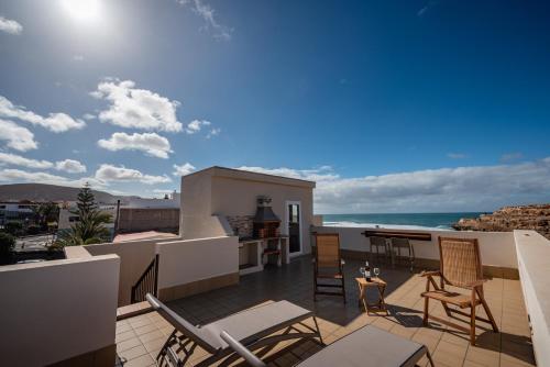 ein Balkon mit Stühlen und einem Tisch und das Meer in der Unterkunft Salitre in Ajuy