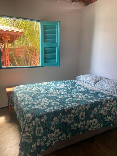 a bedroom with a bed with a blue blanket and a window at Casa Mar Alto in Icapuí
